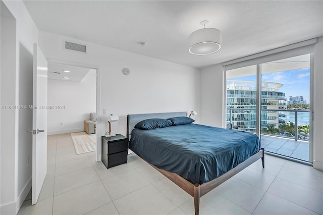 bedroom featuring access to outside, light tile patterned flooring, a water view, and floor to ceiling windows