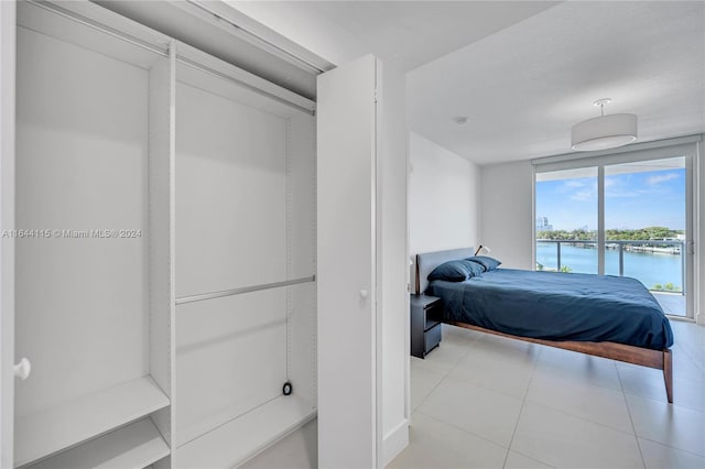 bedroom with light tile patterned flooring, access to exterior, and a water view