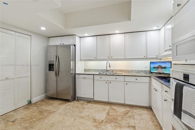 kitchen featuring light tile patterned flooring, sink, stone counters, white appliances, and white cabinetry