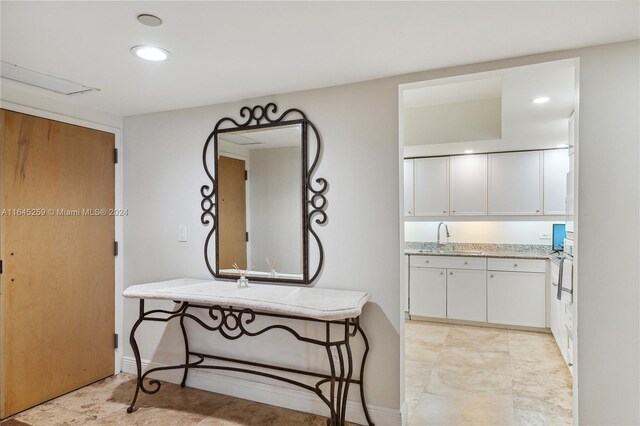 interior space with light tile patterned floors, sink, oven, and white cabinets