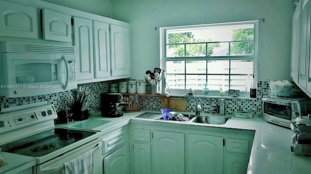 kitchen featuring backsplash, white appliances, white cabinets, and sink