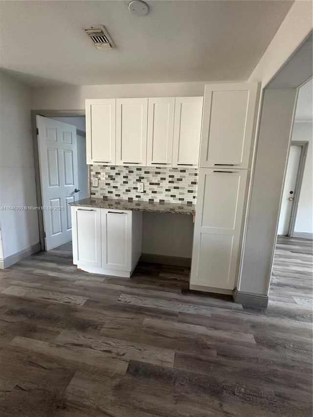 kitchen featuring tasteful backsplash, dark stone countertops, dark hardwood / wood-style flooring, and white cabinets