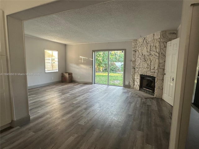 unfurnished living room with a stone fireplace, dark wood-type flooring, and a textured ceiling