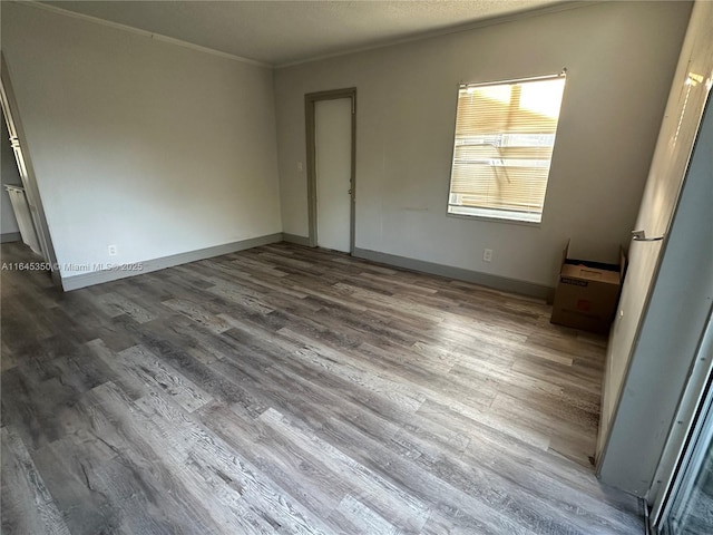 spare room featuring a textured ceiling, wood-type flooring, and crown molding