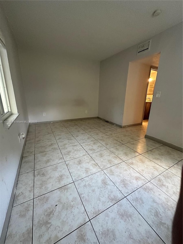 spare room with light tile patterned floors and a textured ceiling