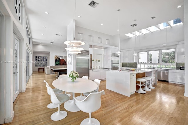 kitchen with a kitchen island, appliances with stainless steel finishes, hanging light fixtures, and white cabinetry