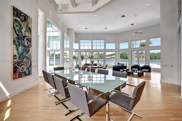 dining room featuring light hardwood / wood-style floors, a water view, a high ceiling, and ceiling fan