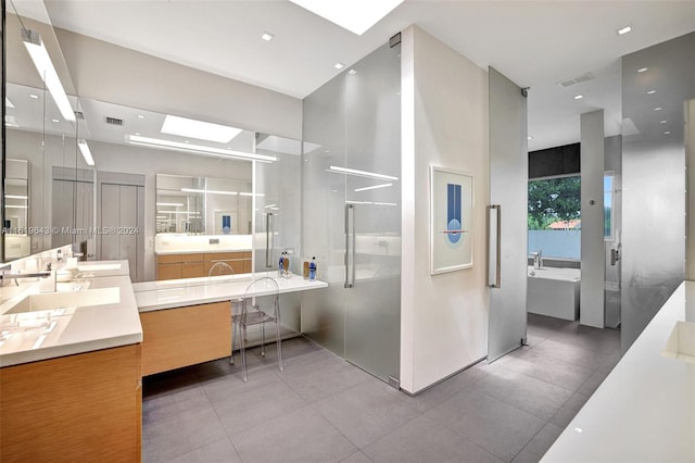 bathroom with vanity, tile patterned floors, a skylight, and a bathing tub