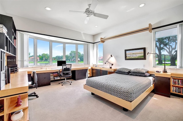 carpeted bedroom with built in desk and ceiling fan