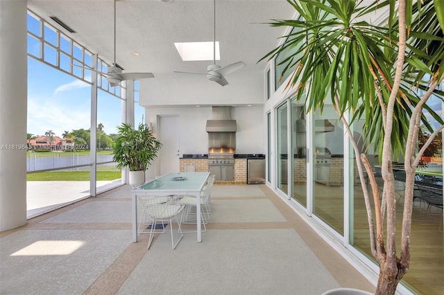 unfurnished sunroom with a water view, a skylight, and ceiling fan