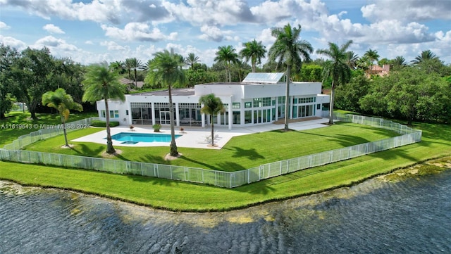 back of property with a patio, a water view, a lawn, and a fenced in pool