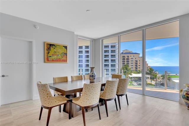 dining space featuring light tile patterned flooring, a wall of windows, and a water view