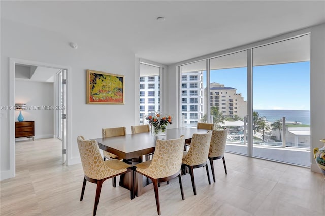 dining room featuring a wall of windows, light tile patterned flooring, and a water view