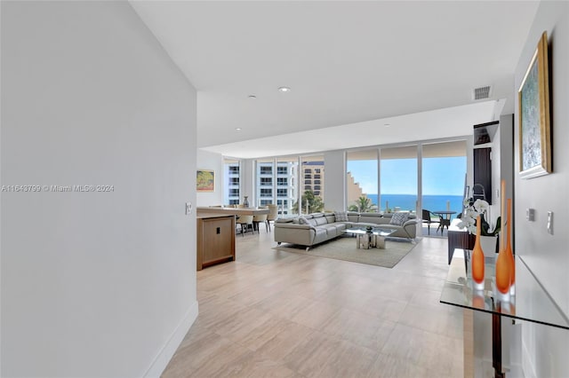 living room featuring light tile patterned flooring, floor to ceiling windows, and a water view