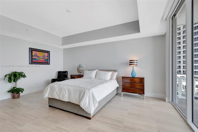 bedroom featuring a tray ceiling, light tile patterned flooring, and access to exterior