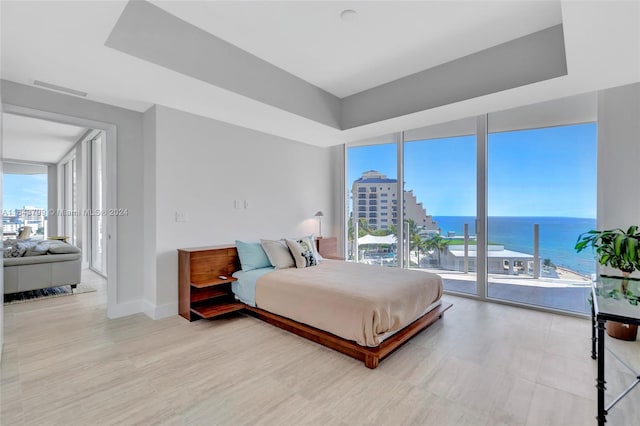 bedroom with floor to ceiling windows, a water view, access to exterior, and multiple windows