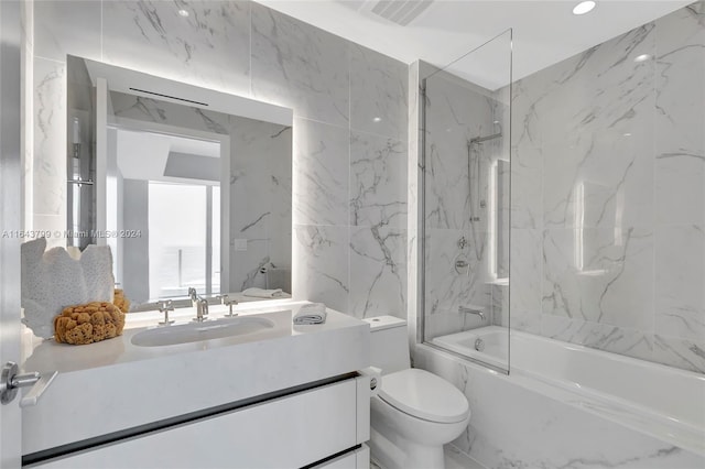 full bathroom featuring tile walls, vanity, shower / bath combination with glass door, and toilet