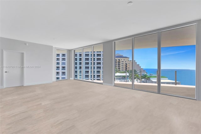 unfurnished room featuring expansive windows, a water view, and light tile patterned floors