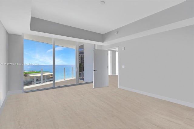 unfurnished room featuring a wall of windows, light tile patterned flooring, and a water view