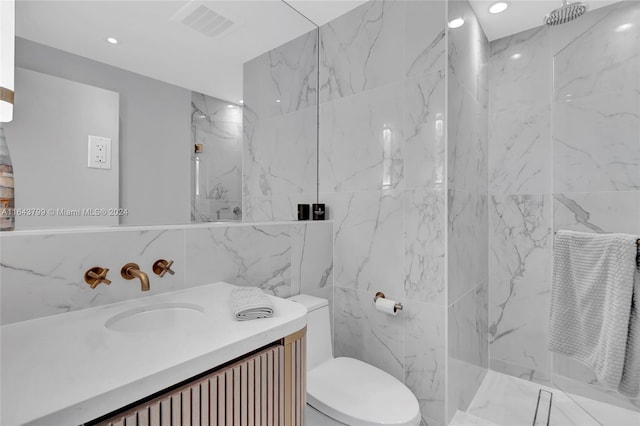 bathroom with tile walls, vanity, a tile shower, and toilet