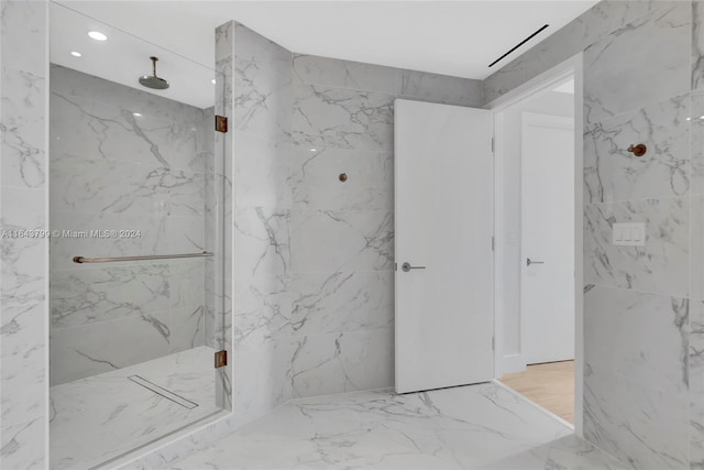 bathroom with tiled shower and hardwood / wood-style flooring