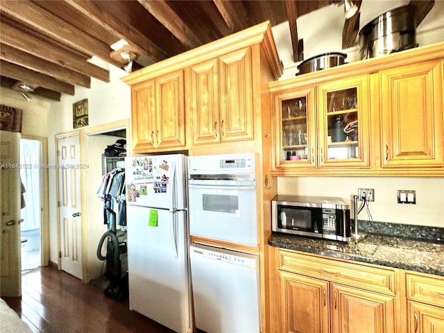 kitchen with white appliances, dark wood-style floors, beamed ceiling, dark stone countertops, and glass insert cabinets