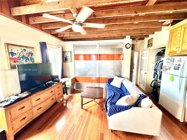 living room with ceiling fan, beamed ceiling, and wood-type flooring