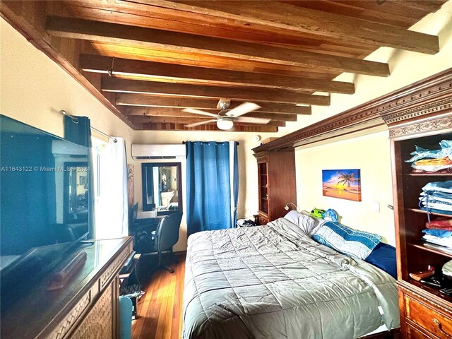 bedroom featuring hardwood / wood-style flooring, a wall mounted AC, and beamed ceiling