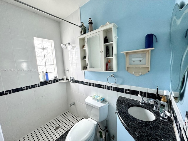 bathroom with toilet, tasteful backsplash, vanity, tile walls, and tiled shower