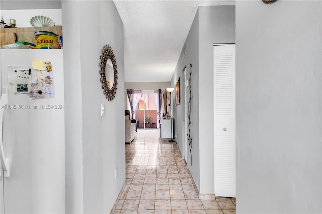 hall featuring light tile patterned floors and a textured ceiling