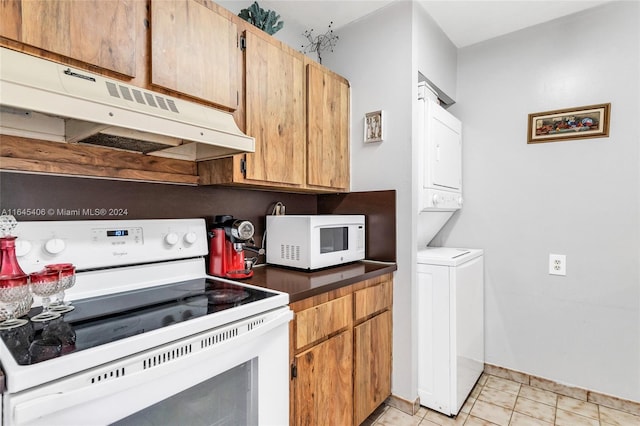 kitchen featuring stacked washer / dryer, light tile patterned flooring, and white appliances