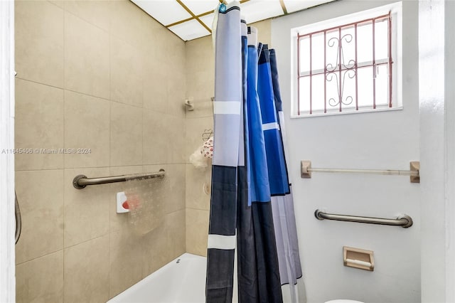 bathroom with shower / bath combination with curtain and toilet