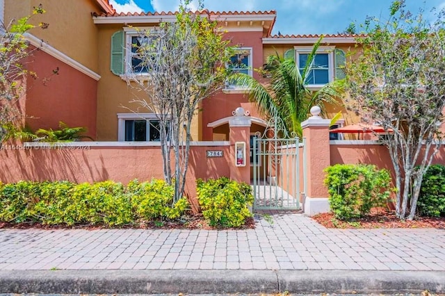 view of front of house with a tile roof, a fenced front yard, a gate, and stucco siding