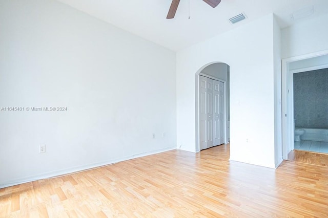 unfurnished room featuring arched walkways, ceiling fan, light wood-type flooring, and visible vents