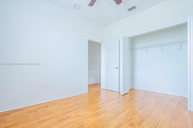 unfurnished bedroom featuring ceiling fan, a closet, and light hardwood / wood-style flooring