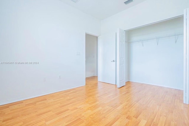 unfurnished bedroom featuring light wood finished floors, a closet, visible vents, and baseboards