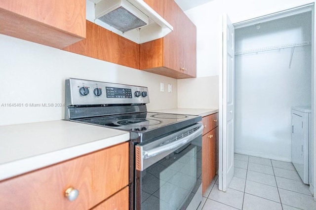 kitchen featuring light tile patterned flooring, light countertops, under cabinet range hood, and stainless steel electric stove