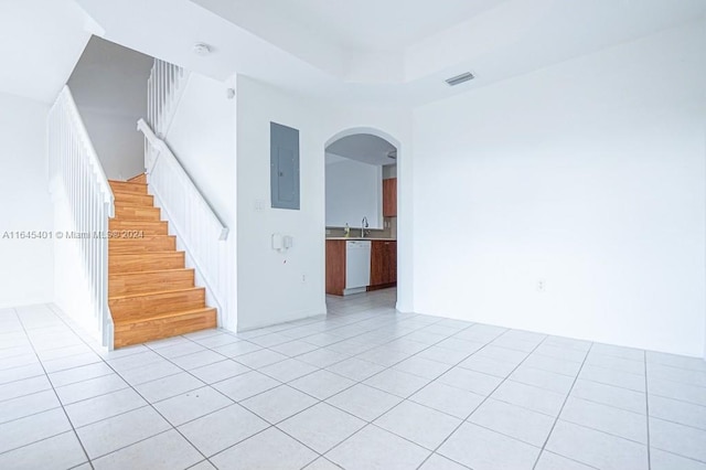 spare room with light tile patterned floors, electric panel, visible vents, arched walkways, and stairway