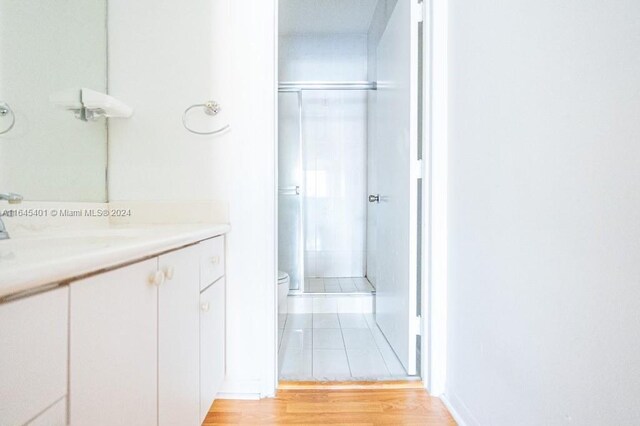 bathroom with wood-type flooring, toilet, walk in shower, and vanity