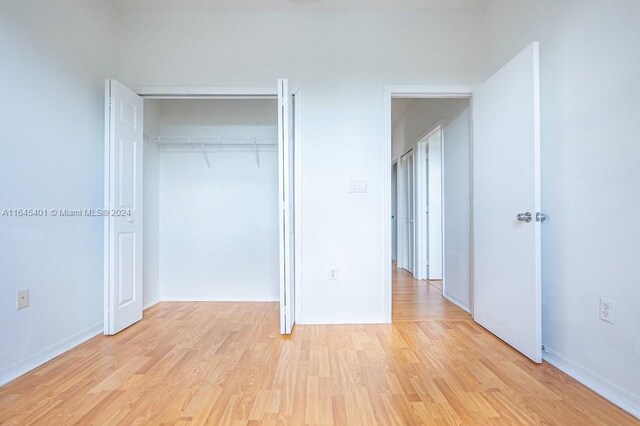 unfurnished bedroom with light hardwood / wood-style flooring and a closet