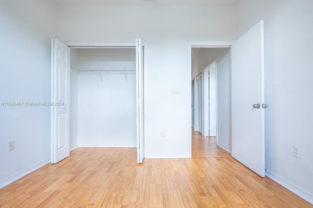 unfurnished bedroom featuring baseboards, a closet, and light wood-style floors