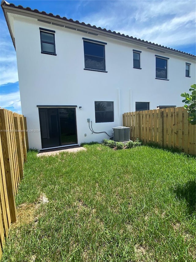 back of property featuring a lawn and central AC