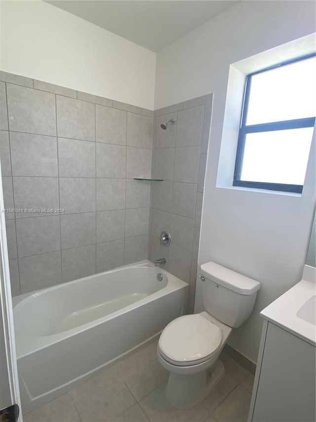 full bathroom with tile patterned floors, tiled shower / bath, vanity, and toilet