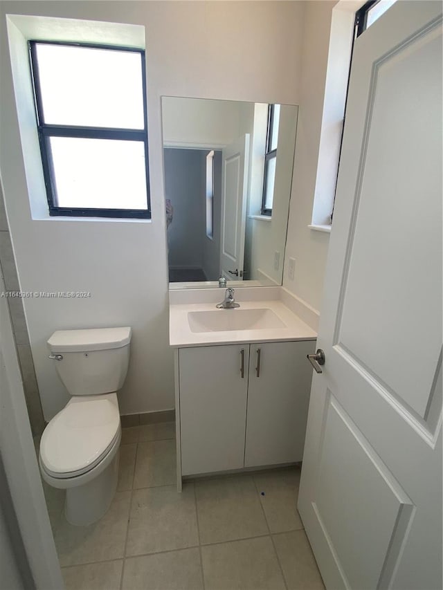 bathroom with a wealth of natural light, tile patterned flooring, vanity, and toilet