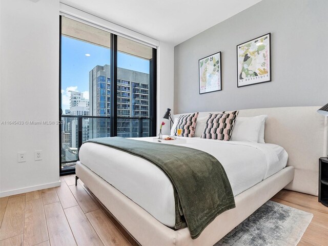 bedroom with expansive windows and light hardwood / wood-style flooring