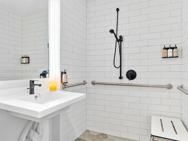 full bathroom featuring a tile shower, a sink, and tile walls