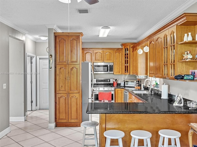 kitchen featuring sink, crown molding, a kitchen bar, kitchen peninsula, and stainless steel appliances