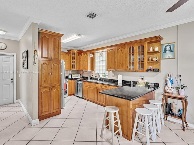 kitchen with ornamental molding, light tile patterned flooring, a kitchen bar, kitchen peninsula, and stainless steel appliances