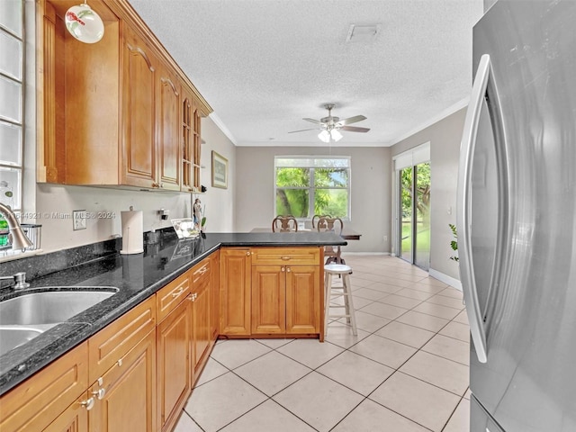 kitchen featuring a kitchen breakfast bar, kitchen peninsula, stainless steel fridge, light tile patterned flooring, and ornamental molding