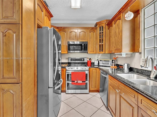 kitchen with sink, stainless steel appliances, dark stone countertops, crown molding, and a textured ceiling